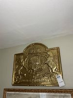 Front view of brass coat of arms plaque mounted on wall