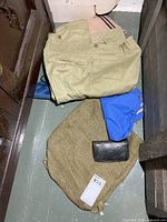 khaki pants, blue nylon bag, burlap sack with leather wallet on top