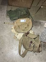 Stack of four canvas military bags in green and khaki shades