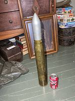 Full view of brass shell casing with aluminum head beside soda can for scale