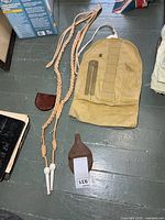 Overall view of lot: two braided ropes, leather flask, small leather pouch, canvas roll with brass polisher