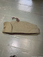 Full view of khaki wool side cap lying flat