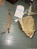 suspenders, folded garments stack including shorts and wool pants, packaged white shirt