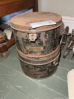 Two stacked cylindrical metal hat boxes showing size and wear