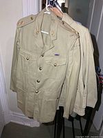 Two khaki Canadian military jackets on hangers