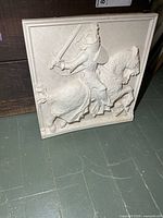 Front view of square plaster relief wall plaque showing knight on horse