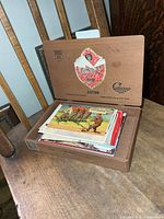 Wooden Astor Cedarg cigar box open, filled with assorted vintage postcards