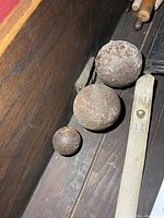 Three cast iron balls of two different sizes on wooden surface