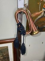 Full view copper and brass bugle hanging, blue cord visible
