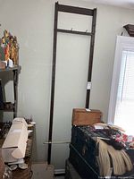 Full view of tall brown rack mounted between floor and ceiling beside window