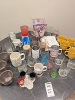 Full view of assorted mugs, glasses, tumblers and coasters on table
