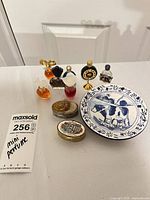 Group shot of all items: 7 perfume bottles, Delft plate, 2 trinket boxes