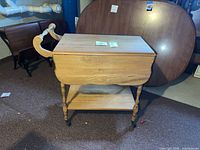 Front view of solid wood drop-leaf tea cart with leaves down, showing handle, legs, lower shelf and casters