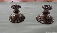 Both ornate silver plate candlesticks on table