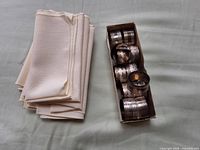 Stack of cloth napkins and open box of metal napkin rings