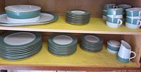 Dinnerware set on shelves showing various plate stacks, cups, serving pieces