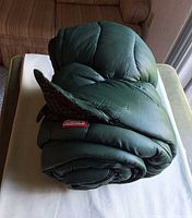 Rolled green Coleman sleeping bag on table