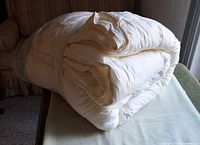 Folded cream king size comforter on table