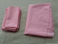 Tablecloth folded alongside stack of eight napkins showing color and pattern