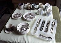 Full view of dinnerware, mugs and flatware on table