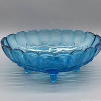 Side view of blue glass footed bowl showing scalloped rim and relief pattern