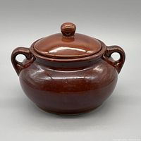 Front view of brown stoneware bean pot with lid and handles