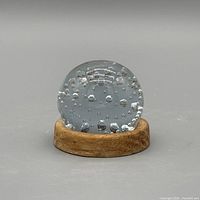 Front view of glass paperweight on wood base showing overall form