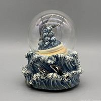 Front view of Elby snow globe showing dolphins, wave base, missing water