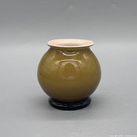 Front view of round mustard glass vase with cream rim on dark base