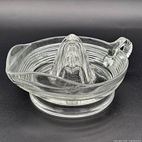 Angled view of clear glass citrus juicer showing spout and base