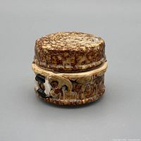 Front view of round brown mottled ceramic trinket box with lid