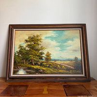 Full view of framed landscape painting on wood surface