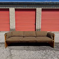Front view of entire sofa against red doors showing full length, frame style, upholstery pattern
