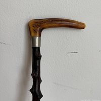 Curved bone handle with metal collar and top of wooden shaft