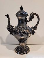 Right side of ornate Portuguese .833 silver tea pot showing scroll handle, pedestal base