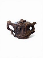 Front angled view showing tree-trunk texture, handle, spout, lid finial