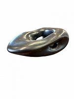 Overall view of smooth dark bronze abstract sculpture with central opening