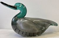 Left side profile of full glass duck showing teal head and grey Fumato body