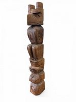 three-quarter view of full totem pole showing figures and chip-carved texture