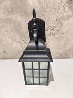 Front view of black outdoor lantern showing frosted glass panes and tapered design