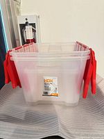 Front view of HDX 49 L clear storage tote showing brand label and red flip-top handles
