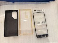 Front view of three phone cases: black Samsung-style, clear OnePlus, packaged generic