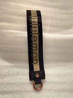 Front view of black woven strap with gold stripe and lululemon text