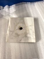 Top view of square white marble base showing central hole and veining