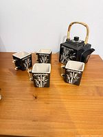 Full tea set on table: teapot with lid and four cups