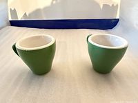 Two green ceramic cups side by side on tabletop