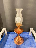 Full view of copper hurricane table lamp with glass chimney and bulb