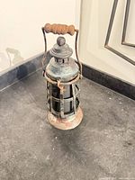Front angled view of complete lantern showing handle, top vent and cage