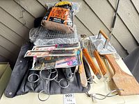 Overview of lot showing smoking chips, grill press, baskets, utensils, lighters and carrying case