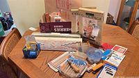 Overall view of craft supplies on table including decoupage kit, carving tools, tapes, brushes, containers